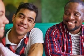 Three students seated at a table smiling at each other